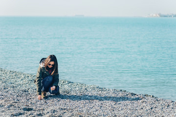 Young woman collects stones on coastline