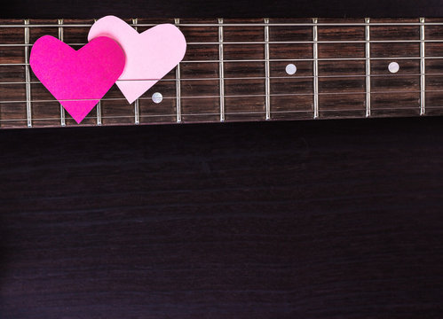 Electric guitar deck with paper hearts on dark background
