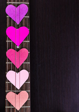 Electric guitar deck with paper hearts on dark background