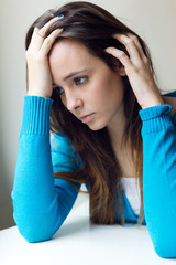 Depressed young woman sitting at home.