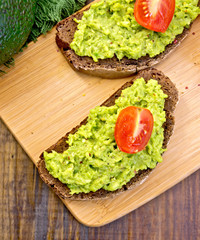 Sandwich with guacamole and tomato on board