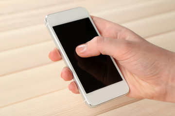 Hand using smart mobile phone on wooden table background