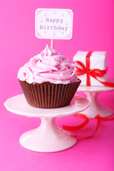 Delicious cupcake with inscription on pink background