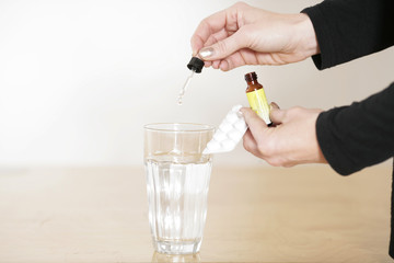 Schmerzmitteltropfen in Wasserglas geben