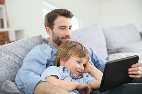 Father with little boy using digital tablet at home