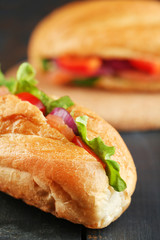 Sandwiches with salmon and vegetables on wooden background