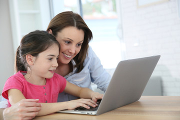 Fototapeta na wymiar Woman with girl doing homework on laptop