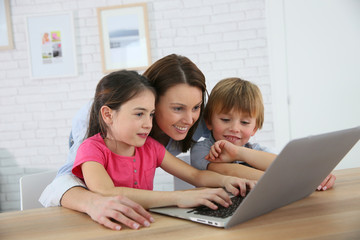 Mother with kids playing on laptop computer