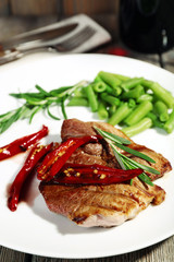 Steak with vegetables on plate on table close up