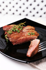 Steak with herbs on plate on wooden background