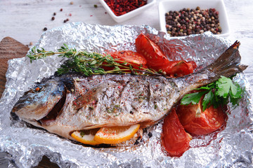 Tasty baked fish in foil on table close-up