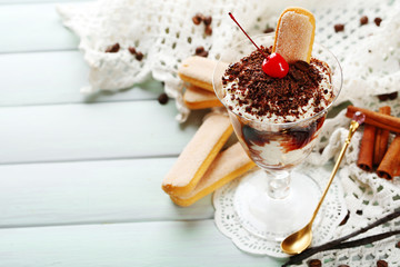 Tasty tiramisu dessert in glass, on wooden background