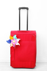 Red suitcase with toy flower isolated on white