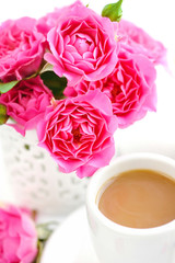 Cups of coffee and pink roses on white background