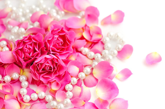 Pink roses and pearls on white background
