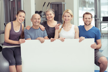 gemischte gruppe zeigt ein plakat im fitness-studio