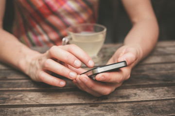 Fototapeta na wymiar Young woman drinking tea and using her phone