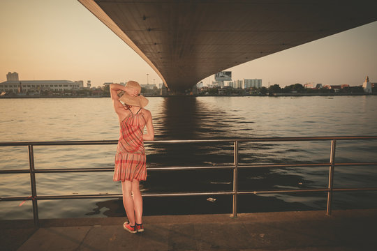Young woman under bridge at sunset
