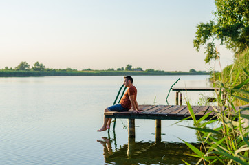 Young man sitting relaxing and enjoying the view from dock