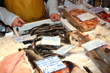 fishmonger sells the fresh fish at the market - obrazy, fototapety, plakaty