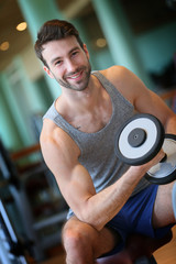 Fototapeta na wymiar Man lifting weights in fitness center