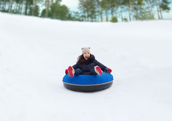 happy teenage girl sliding down on snow tube