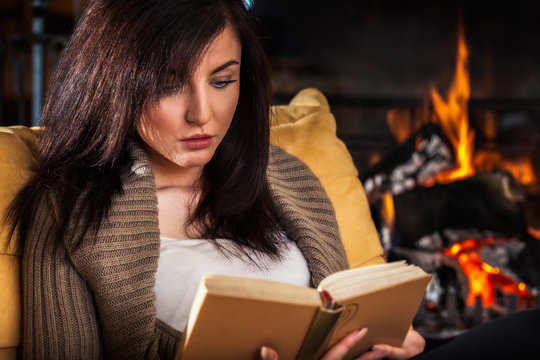 Woman Reading A Book By Fireplace