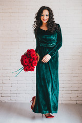 Beautiful woman in a green dress and red shoes with red roses