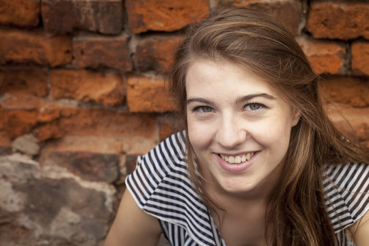 Cute young girl close-up portrait near a brick wall.