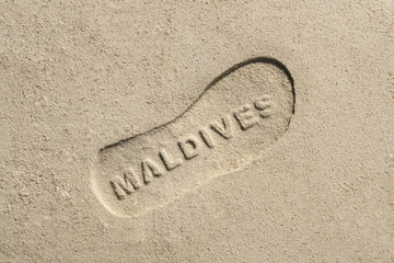 Maldives written into sand  background