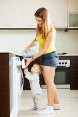 long-haired woman  and child using washing machine