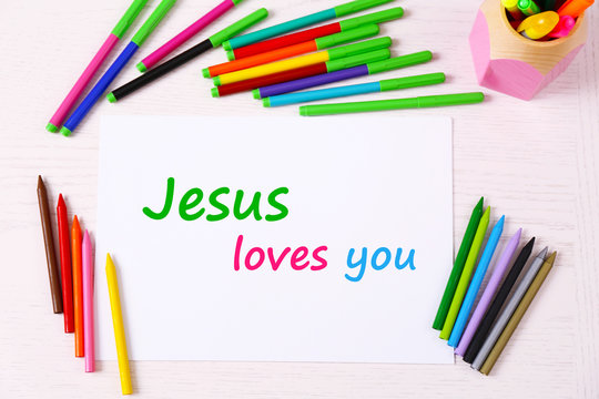 Jesus loves you text on paper on table background