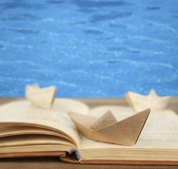 Origami boats on old book on sea background
