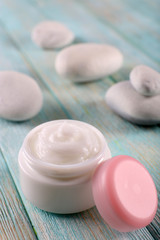 Obraz na płótnie Canvas Cosmetic cream with spa stones on wooden background
