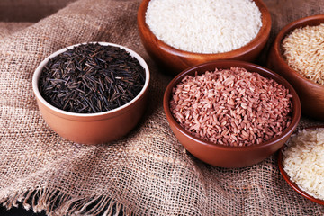Different kinds of rice in bowls on sackcloth background