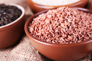 Different kinds of rice in bowls on sackcloth background