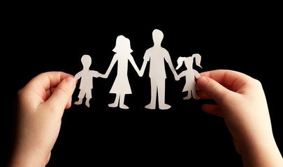 Fototapeta na wymiar Paper family in child hands on black background