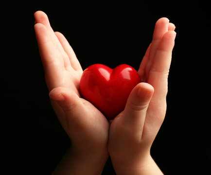 Heart In Child Hands On Black Background