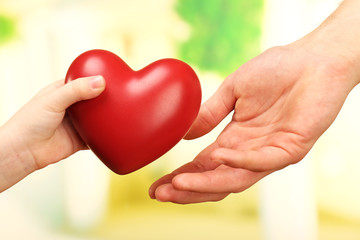 Fototapeta na wymiar Child and father hands with heart on bright background