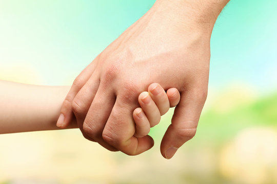 Child and father hands on bright background