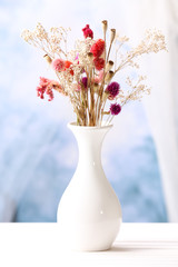 Bouquet of dried flowers in vase on light background