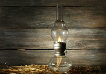 Kerosene lamp with hay on rustic wooden planks background