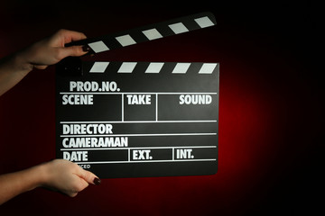 Movie clapper in female hand on dark color background
