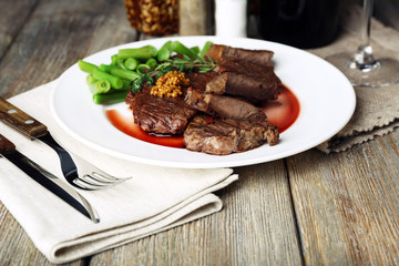 Steak with wine sauce on plate on wooden table