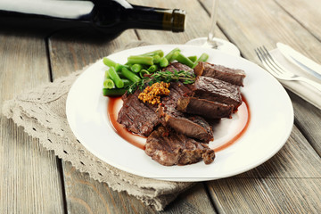 Steak on plate with bottle of wine on wooden background