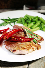 Steak with vegetables on plate on table close up