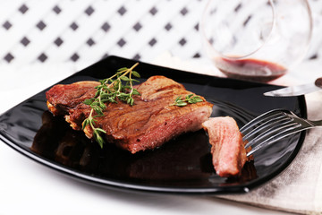 Steak with herbs on plate with wine on wooden background