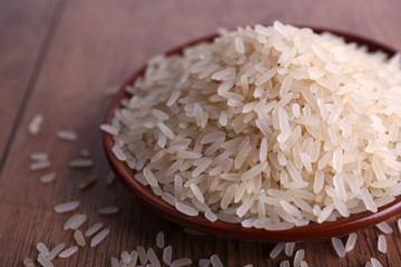 Grain of rice on plate on wooden background
