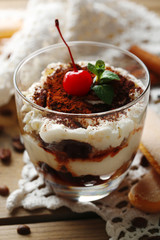 Tasty tiramisu dessert in glass, on napkin, on wooden