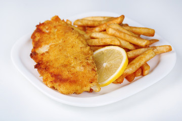 Breaded fried fish fillet and potatoes with sliced lemon